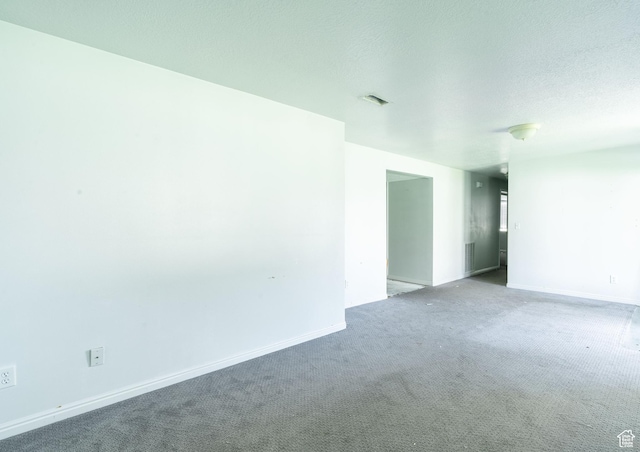 carpeted spare room featuring baseboards and a textured ceiling