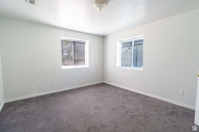 unfurnished room with dark colored carpet, baseboards, and a textured ceiling