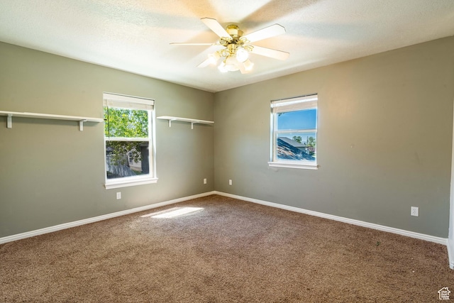 empty room with carpet floors, ceiling fan, baseboards, and a textured ceiling