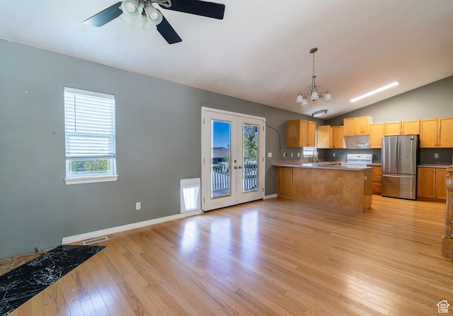 kitchen featuring freestanding refrigerator, lofted ceiling, light wood-type flooring, a peninsula, and a chandelier