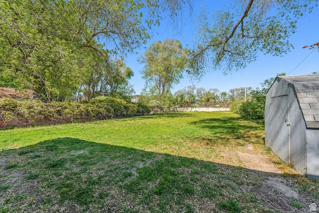 view of grassy yard featuring a storage unit and an outbuilding