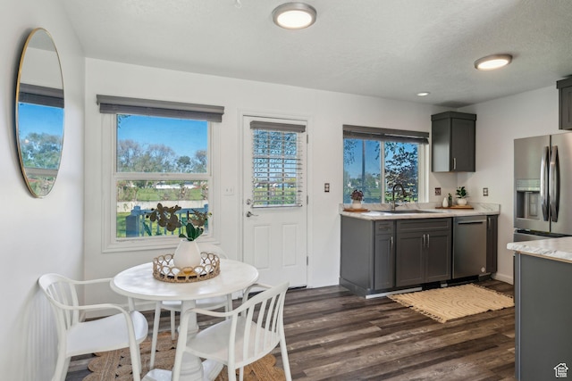 kitchen featuring stainless steel appliances, a sink, light countertops, dark wood-type flooring, and a textured ceiling