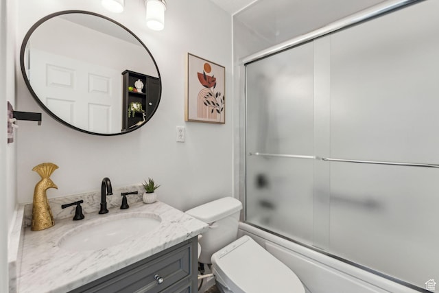full bath featuring vanity, toilet, and shower / bath combination with glass door