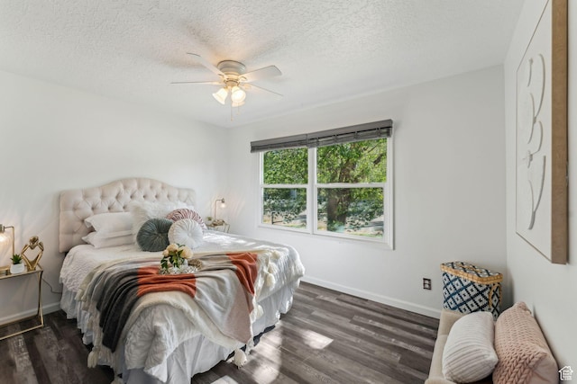 bedroom with dark wood-type flooring, baseboards, a textured ceiling, and a ceiling fan