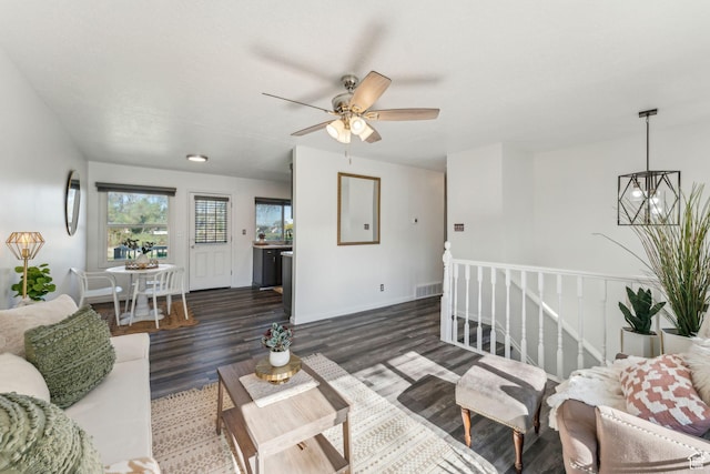 living room featuring wood finished floors, a ceiling fan, a chandelier, and baseboards