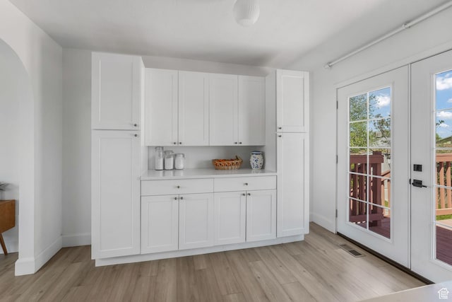 kitchen with french doors, light wood-type flooring, white cabinets, and light countertops
