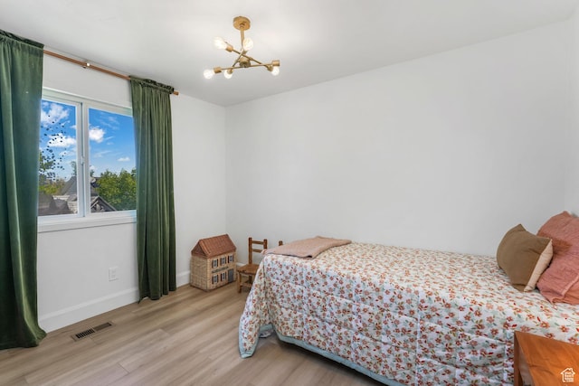 bedroom featuring a chandelier, light wood-type flooring, and baseboards