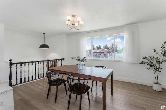 dining area with light wood-style flooring, a chandelier, and baseboards