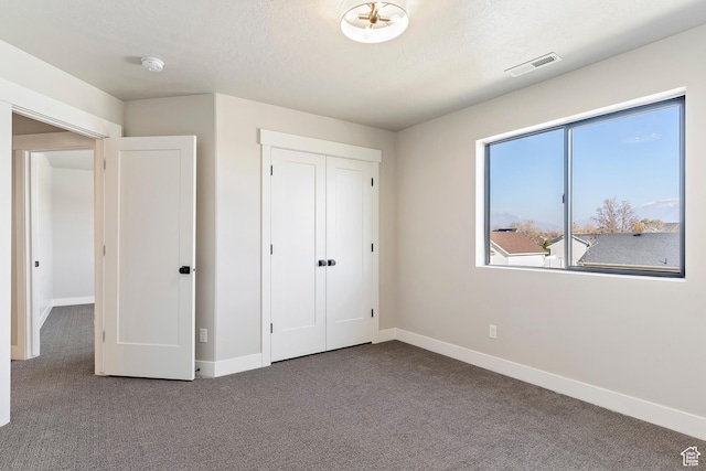unfurnished bedroom featuring carpet floors, baseboards, a closet, and a textured ceiling