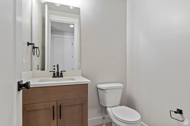 bathroom with baseboards, toilet, and vanity