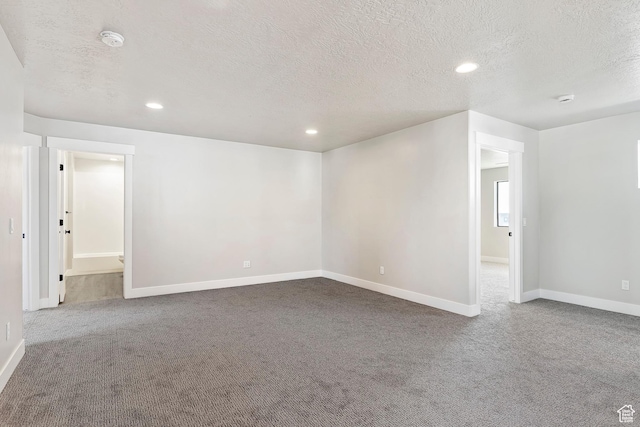 carpeted empty room featuring a textured ceiling, a smoke detector, recessed lighting, and baseboards