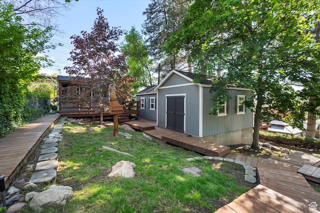 view of green lawn featuring a wooden deck, an outbuilding, and a storage shed