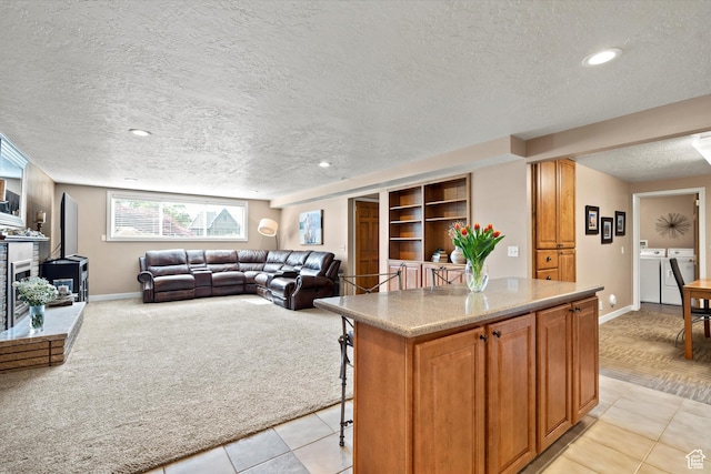kitchen featuring separate washer and dryer, a textured ceiling, baseboards, a kitchen bar, and light countertops