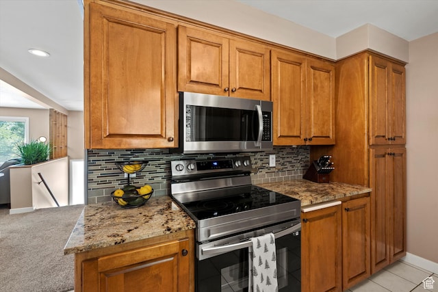 kitchen with appliances with stainless steel finishes, brown cabinets, backsplash, and light stone counters
