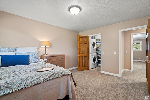 bedroom featuring stacked washer and clothes dryer, carpet flooring, baseboards, and a textured ceiling