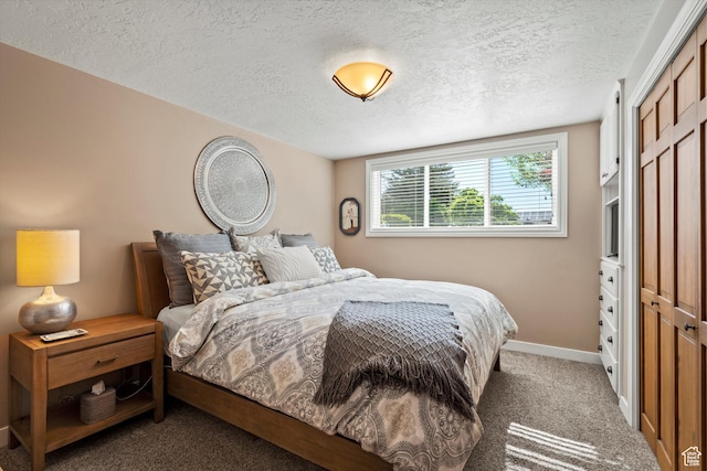 bedroom featuring a textured ceiling, a closet, carpet floors, and baseboards