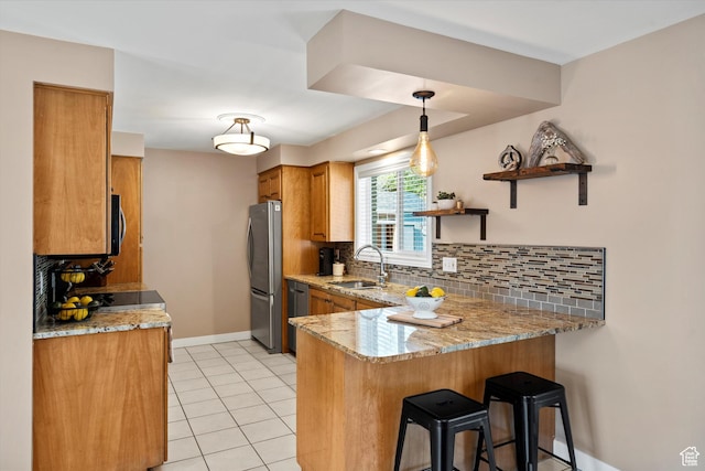 kitchen with a sink, freestanding refrigerator, a peninsula, brown cabinetry, and backsplash