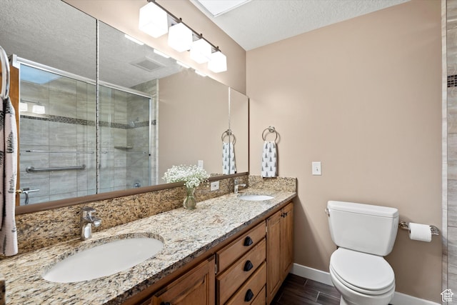 full bath with toilet, a shower stall, baseboards, a textured ceiling, and double vanity