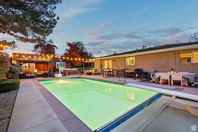 pool at dusk with an outdoor hangout area, a gazebo, a patio, and a diving board