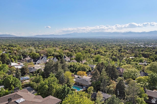 aerial perspective of suburban area with a mountain backdrop, a forest, and a pool area