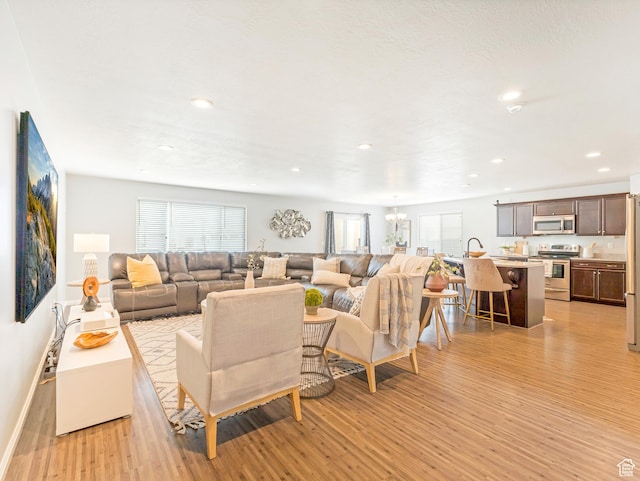 living room featuring light wood-style floors, healthy amount of natural light, a chandelier, recessed lighting, and baseboards