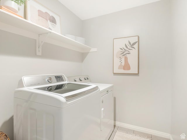 laundry room featuring independent washer and dryer, light tile patterned floors, and baseboards