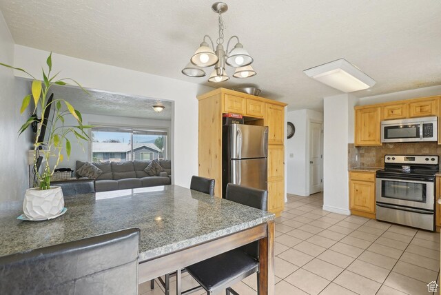 4372 S Wildrose Dr W, West Valley City, UT 84120 - kitchen with appliances with stainless steel finishes, a chandelier, light tile patterned flooring, tasteful backsplash, and open floor plan