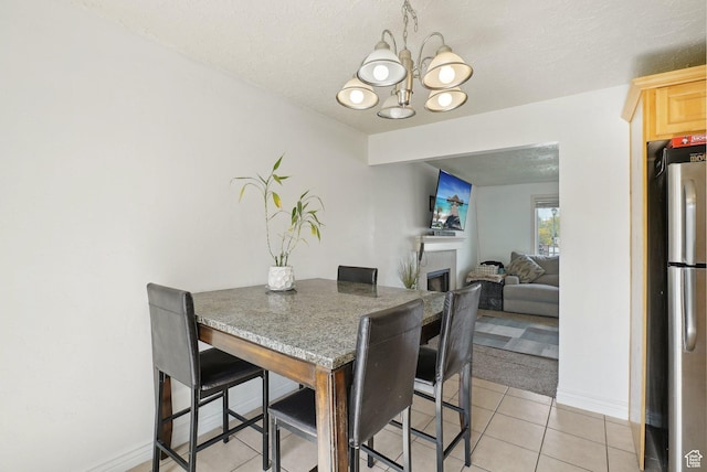 4372 S Wildrose Dr W, West Valley City, UT 84120 - dining area featuring a chandelier, light tile patterned floors, baseboards, a fireplace, and a textured ceiling