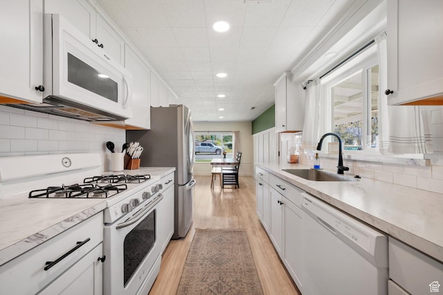 kitchen with white appliances, a sink, light wood-style flooring, recessed lighting, and light countertops