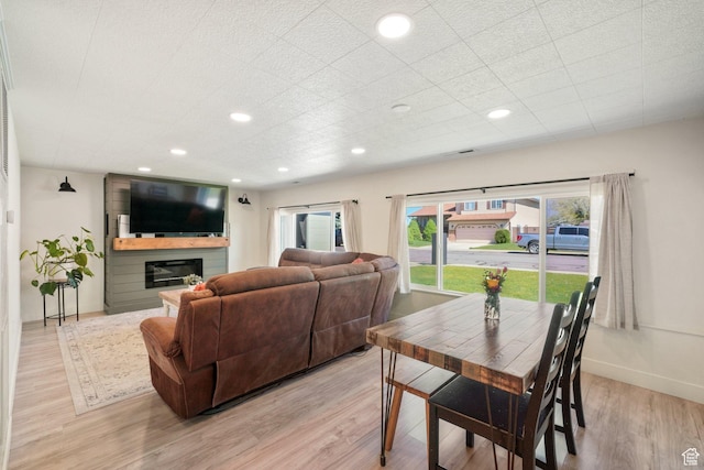 dining area featuring light wood-style flooring, a glass covered fireplace, recessed lighting, and baseboards