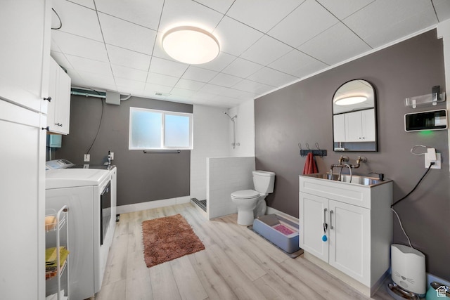 full bath with washing machine and dryer, tiled shower, toilet, wood finished floors, and vanity