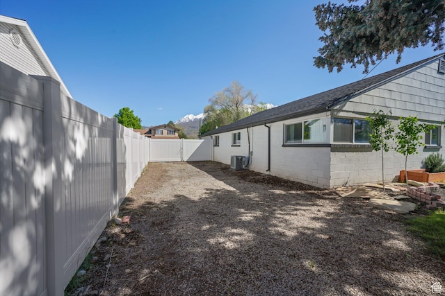 fenced backyard with central air condition unit and a gate