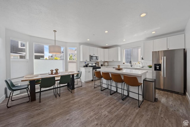 3850 W Kinglassie Ln, Taylorsville, UT 84129 - kitchen with appliances with stainless steel finishes, white cabinets, a breakfast bar, dark wood-style flooring, and recessed lighting