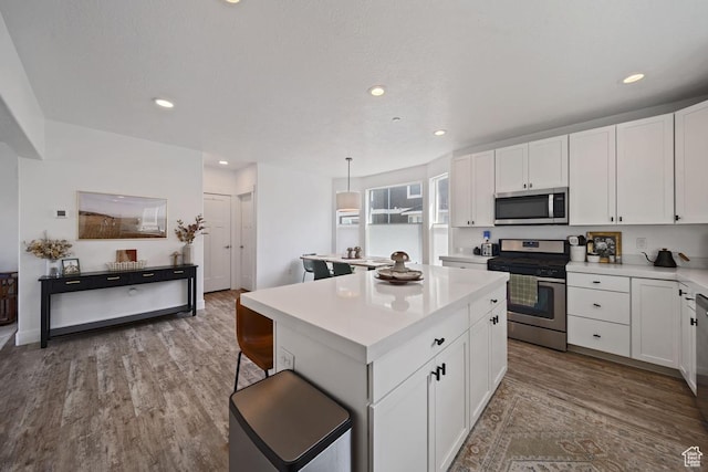 3850 W Kinglassie Ln, Taylorsville, UT 84129 - kitchen featuring stainless steel appliances, a kitchen island, light countertops, wood finished floors, and white cabinets
