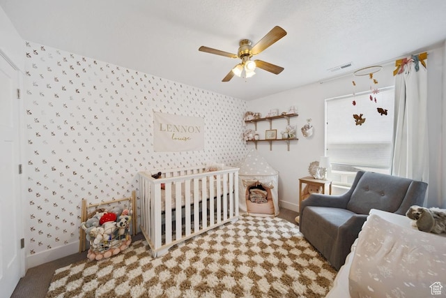 3850 W Kinglassie Ln, Taylorsville, UT 84129 - carpeted bedroom featuring wallpapered walls, baseboards, a crib, an accent wall, and ceiling fan
