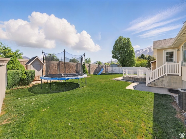 view of yard with a trampoline, a playground, a storage unit, and central AC unit