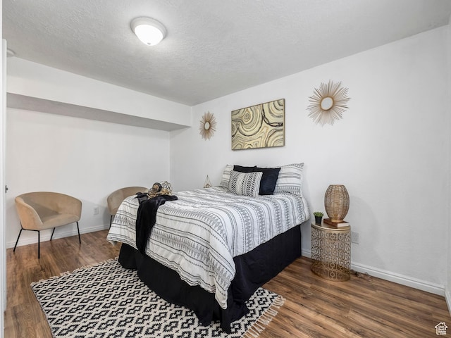 bedroom featuring wood finished floors, baseboards, and a textured ceiling