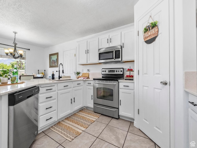 kitchen with appliances with stainless steel finishes, a sink, a chandelier, a textured ceiling, and light tile patterned floors