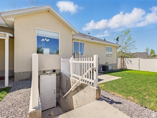 rear view of house featuring stucco siding and central AC