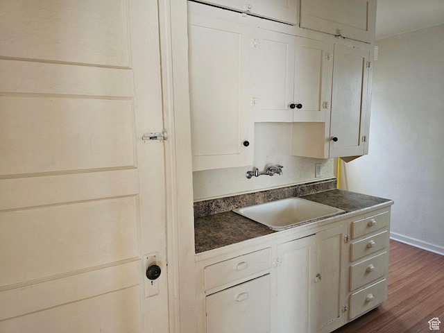383 N 100 E, Price, UT 84501 - kitchen featuring dark countertops, a sink, dark wood-style flooring, baseboards, and white cabinetry