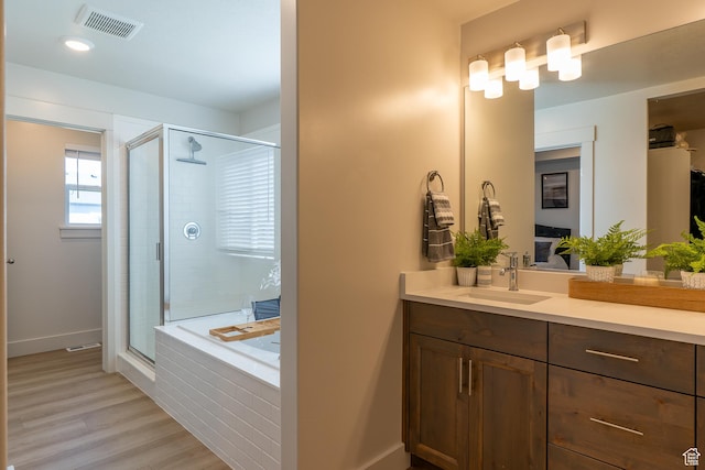 bathroom with a shower stall, vanity, wood finished floors, and a garden tub
