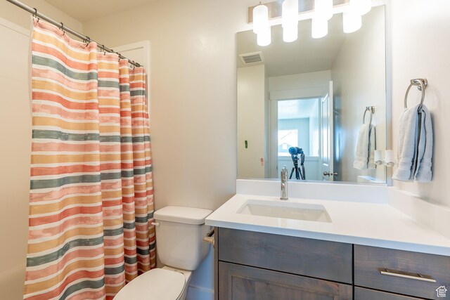 full bath with toilet, vanity, and curtained shower