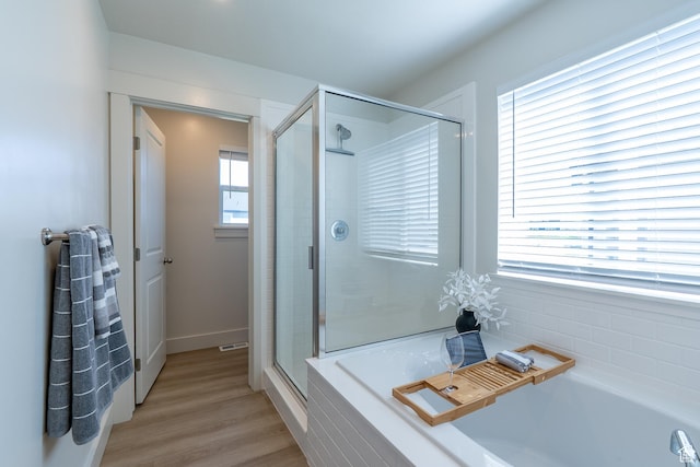 bathroom featuring a stall shower, a bath, and wood finished floors
