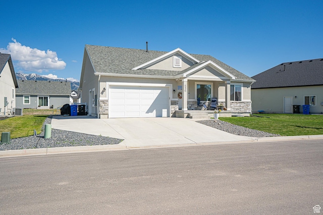 view of front of house featuring stone siding, stucco siding, a garage, and a front lawn