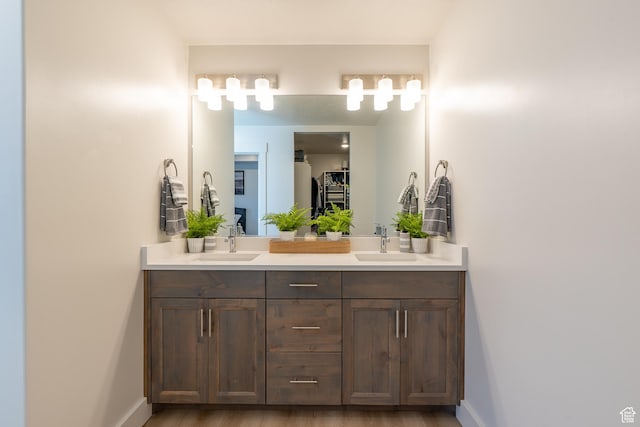 full bath with double vanity, baseboards, and wood finished floors