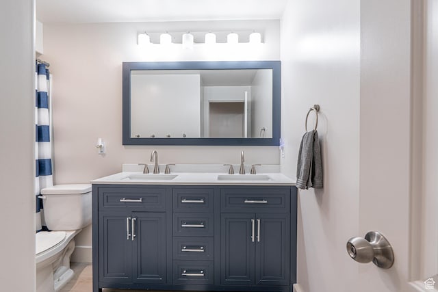 full bath with toilet, double vanity, and baseboards