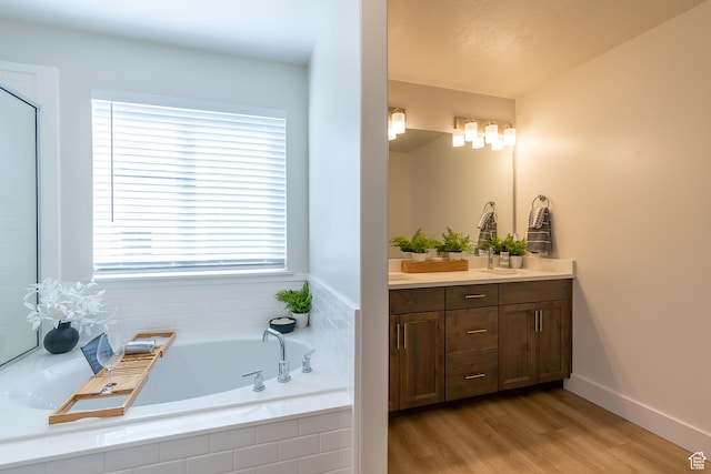 bathroom featuring vanity, a bath, wood finished floors, and baseboards