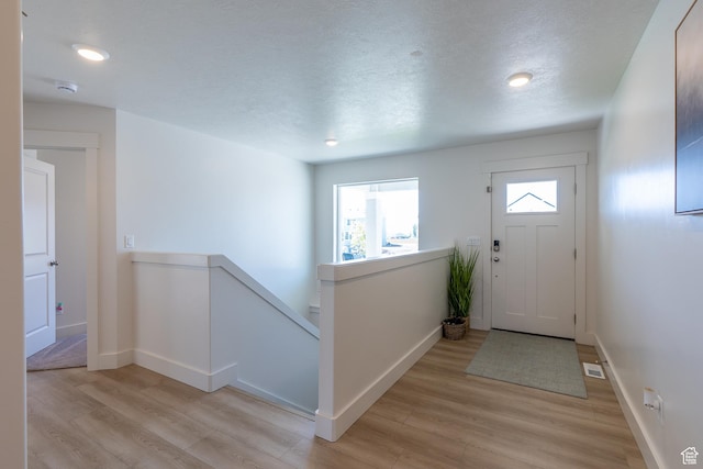 foyer featuring light wood-style floors, baseboards, a textured ceiling, and recessed lighting