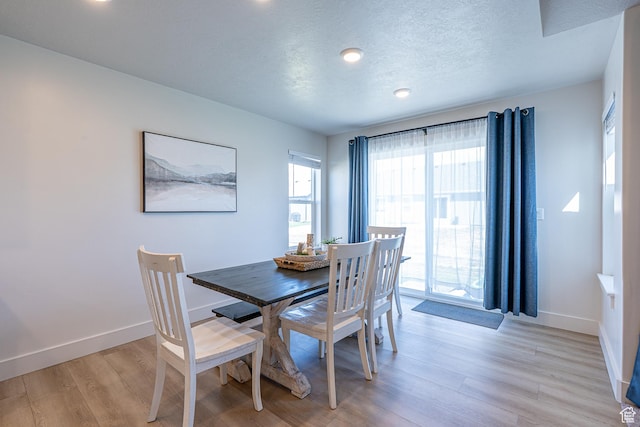 dining area featuring light wood-style floors, baseboards, a textured ceiling, and recessed lighting