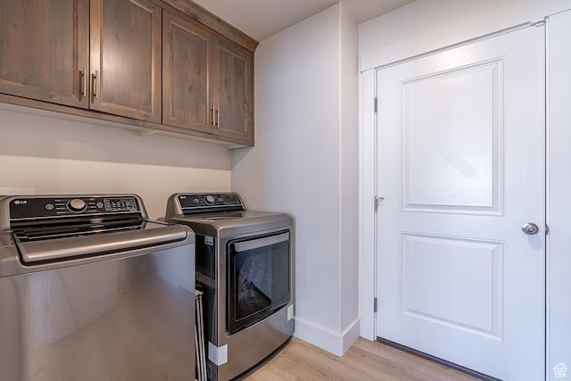 clothes washing area with independent washer and dryer, light wood-style flooring, cabinet space, and baseboards